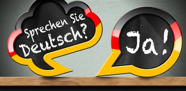 3D illustration of two speech bubbles with German flag and question, Sprechen Sie Deutsch? and Ja! (Do you speak German? and Yes!). On a wooden shelf with a wall on background.